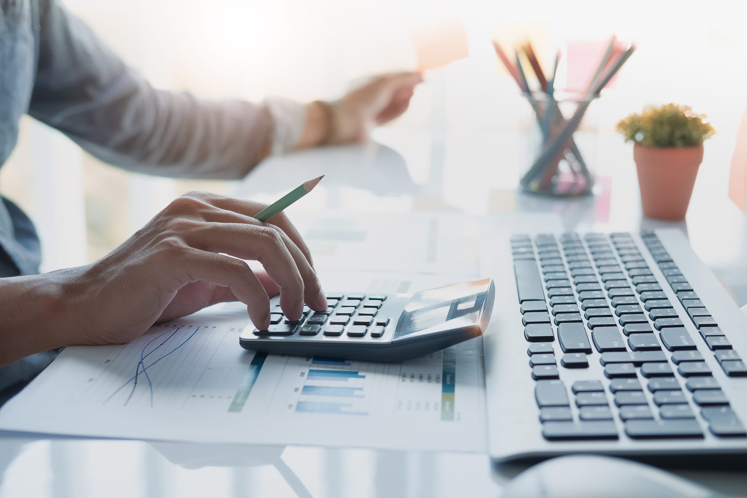 Personne tenant un crayon et utilisant une calculatrice