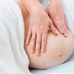 Gros plan de mains posées sur un ventre de femme enceinte
