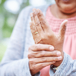 Gros plan sur une personne âgée qui se prend la main car elle souffre d'arthrite